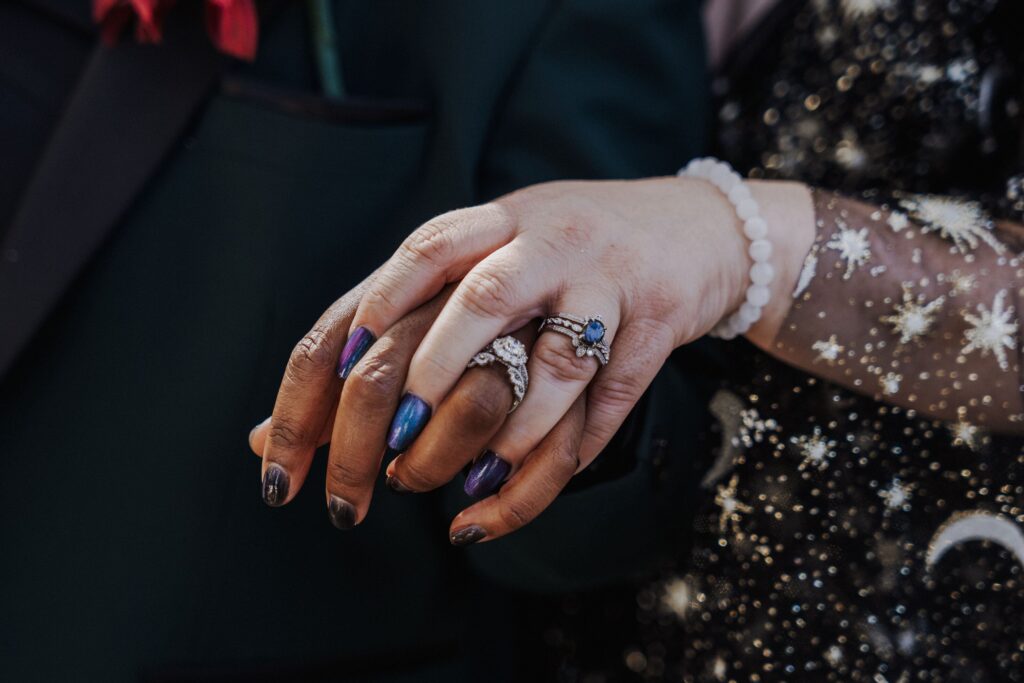 detail shot of two brides holing hands in a way that shows off their rings