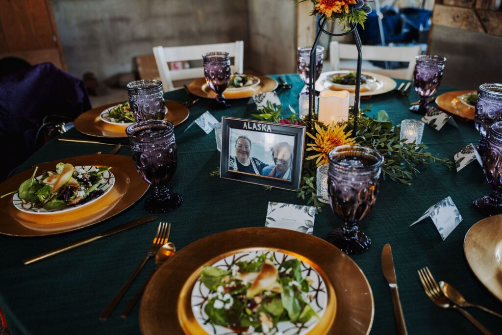 dark and moody styling of a Starlight Meadow wedding reception table with burnished gold chargers and purple glass goblets