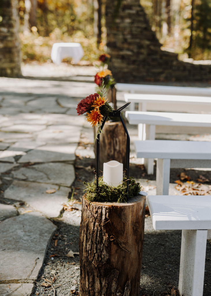 Moss, lanterns, and autumn color along Rachel & Nisha's ceremony aisle.